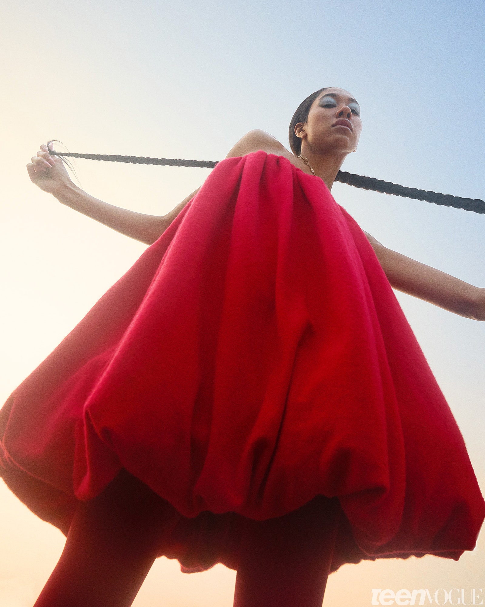 Aoki Lee Simmons standing in red balloon dress against the sky.