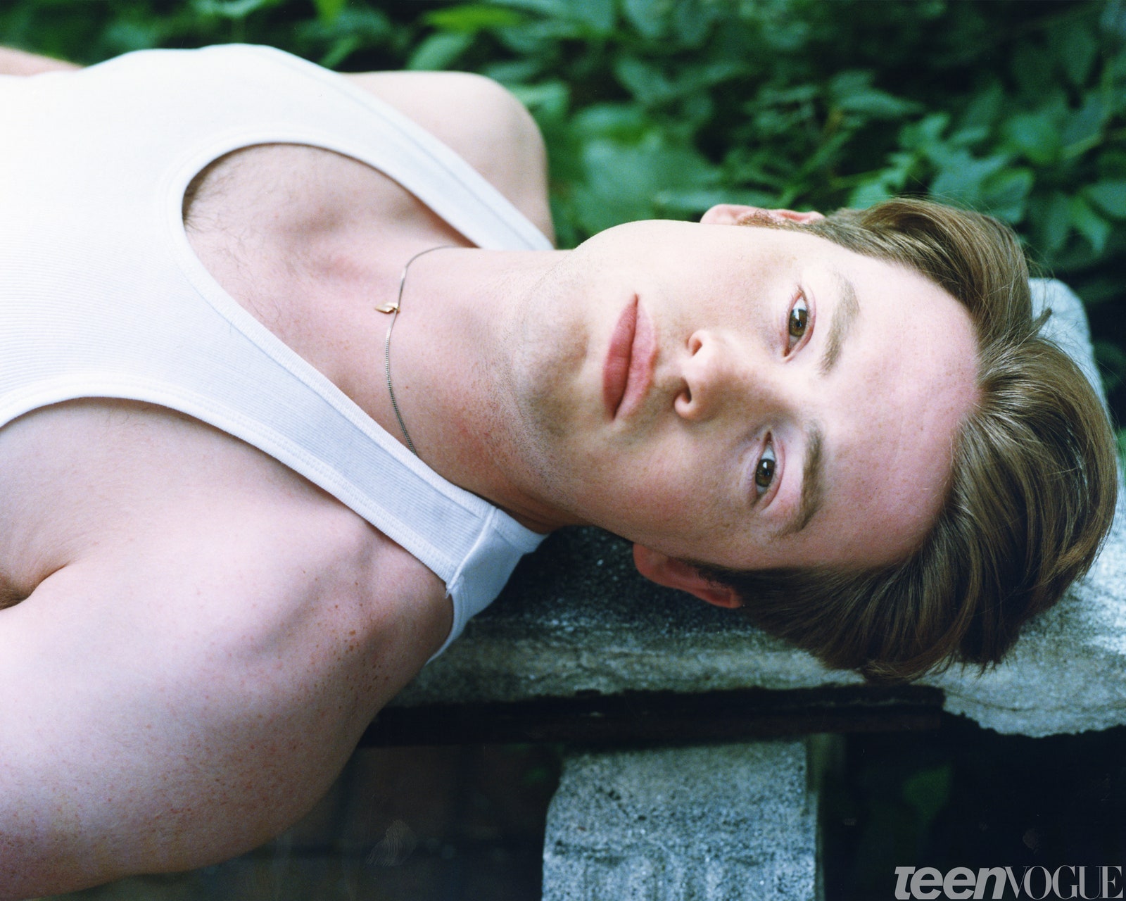 Kit Connor in a white tank top on a bench.